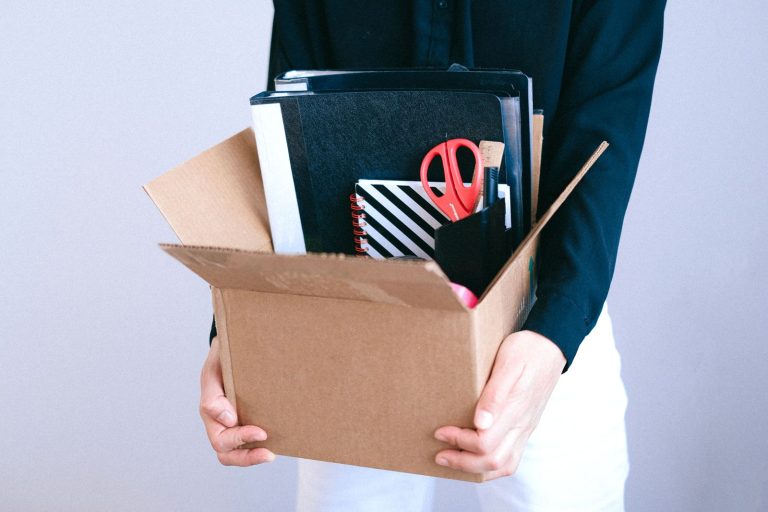 Salarié quittant son poste avec un carton contenant ses affaires de bureau